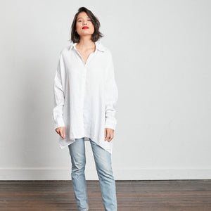 Model faces the camera wearing white oversized linen boyfriend shirt wearing jeans and bright red lipstick
